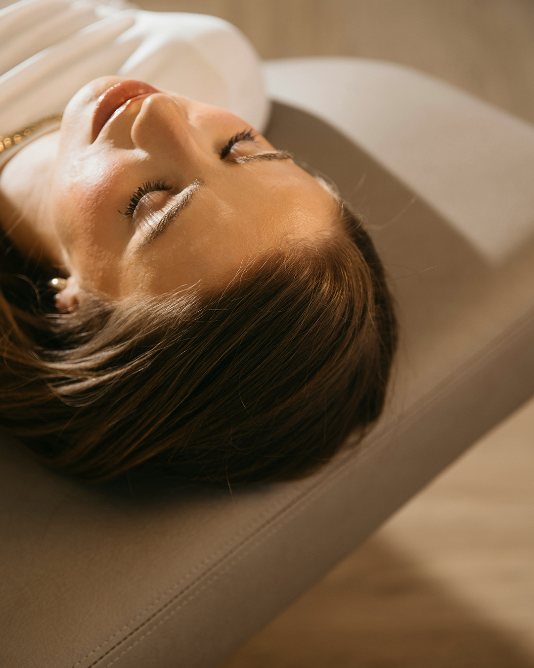 Mujer acostada en una camilla de tratamiento recibiendo terapia de compresión de piernas con presoterapia.